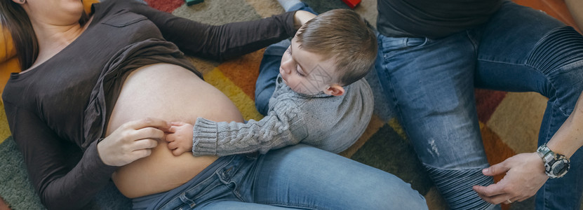 小男孩在父亲的监视下抚摸其怀孕母亲的肚子图片
