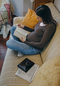 孕妇在沙发上读一本书图片