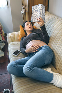 孕妇在客厅沙发上读一本书图片