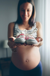 孕妇在卧室中展示婴儿运动鞋图片