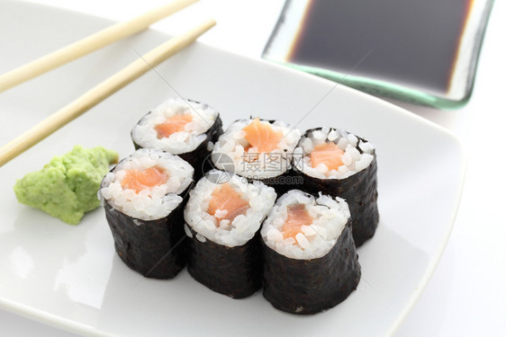 马哈在白背景下配有筷子和酱油的寿司图片