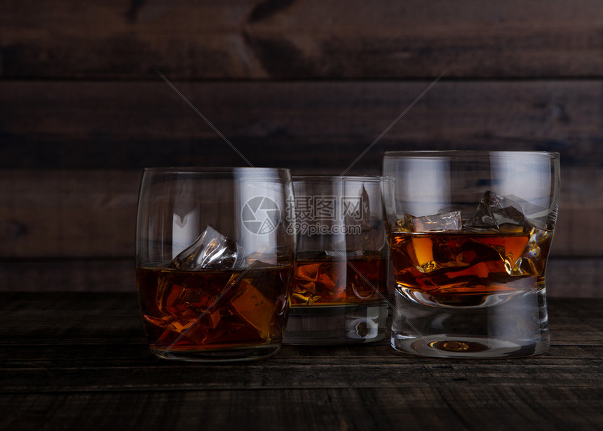 杯子威士忌木制桌背景上的冰块图片
