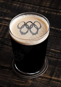 玻璃杯啤酒顶上木底有奥林匹克形状图片