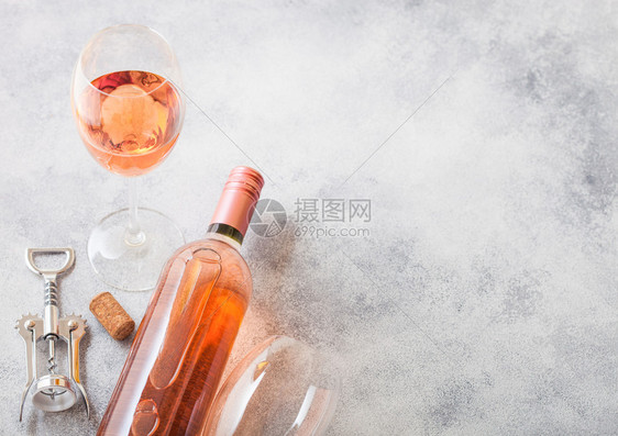 和粉红玫瑰酒的瓶子和开放在石头厨房桌背景上图片