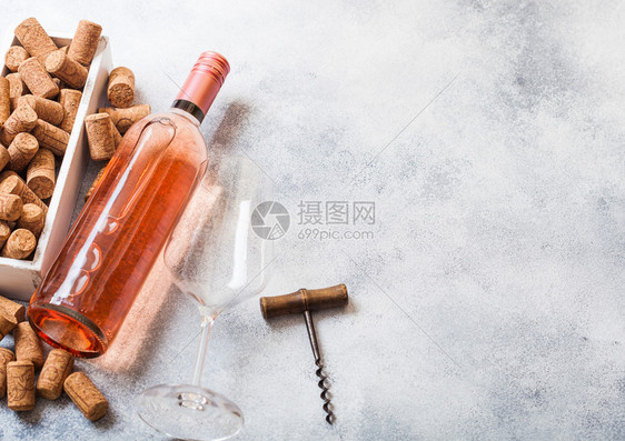 和粉红玫瑰葡萄酒的瓶子里面装有软木箱和开瓶器放在石头厨房桌背景上图片