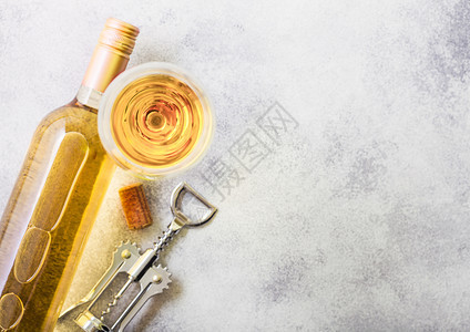 和白葡萄酒的瓶子和开器在石头厨房桌背景顶端视图图片