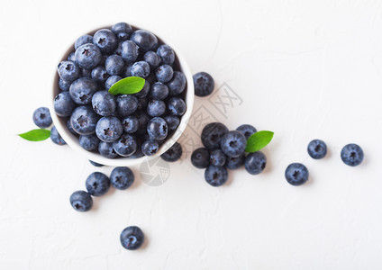 白色背景瓷碗叶子的新鲜有机蓝莓顶部视图图片