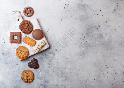 在石头厨房背景的木板上挑选燕麦和巧克力饼干图片