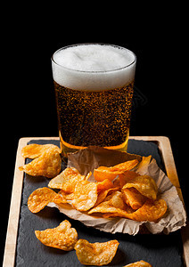 杯啤酒和土豆脆饼在石板上的零食黑色背景图片