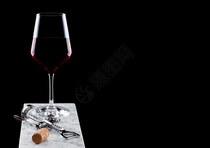 大理石板上有玻璃红葡萄酒装有开瓶器和黑色的子图片