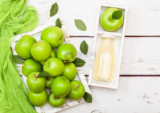 玻璃瓶新鲜有机苹果汁在木本底盒装绿苹果图片