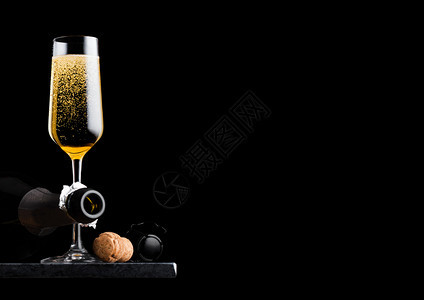 优雅的黄色香槟杯子装有软木和铁丝笼还有黑底大理石板上的瓶子图片