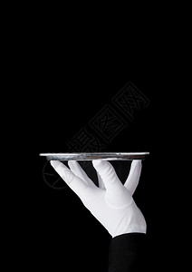 身戴白手套的女仆在黑色背景上拿着不锈钢盘图片