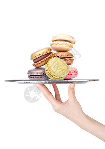 手持托盘面带甜美的马卡龙饼在白色背景上加糖图片