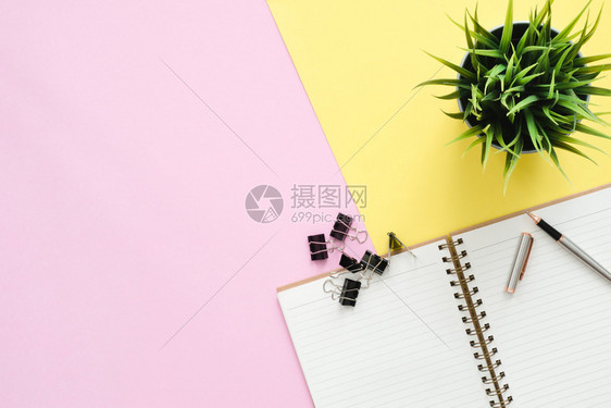 工作空间办公桌的顶层用粉红色黄面纸彩背景的笔记本和铅植物制成顶层视图复制空间平面摄影图片