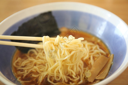 筷子碗夹起木桌上的日式清汤面背景