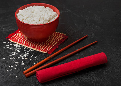 红碗加煮的有机巴斯马提茉米饭红筷子和甜豆酱加竹制地垫红皮巾加黑石图片