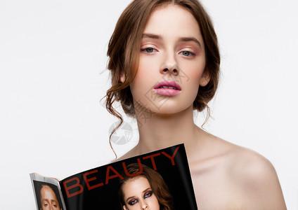 美年轻女孩带着时装杂志在白色背景的杂志封面上画像图片