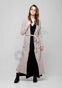 年轻漂亮的时装模特穿着灰色背景的编织服装图片