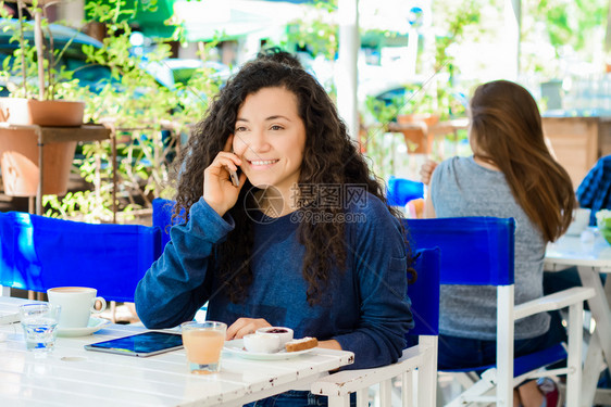 美丽的年轻拉丁女人肖像在咖啡店的手机上聊天图片