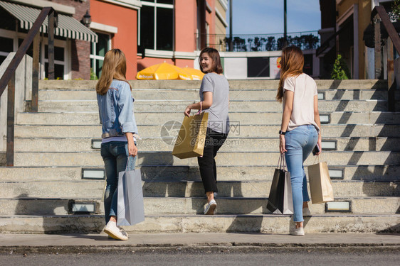 年轻女展示自己在温暖阳光下购物袋中得到的东西图片