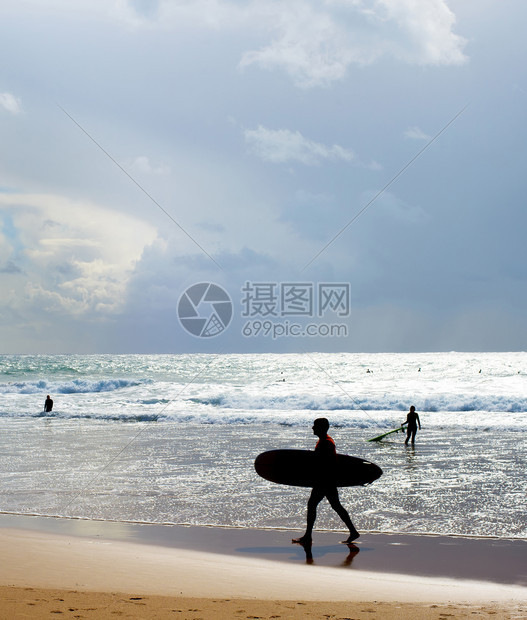 沙滩上有冲浪板的者浅影长脚下图片