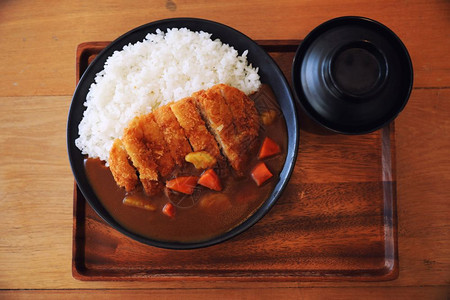 东京食种咖喱米饭用木制桌上的日本食煎猪肉背景