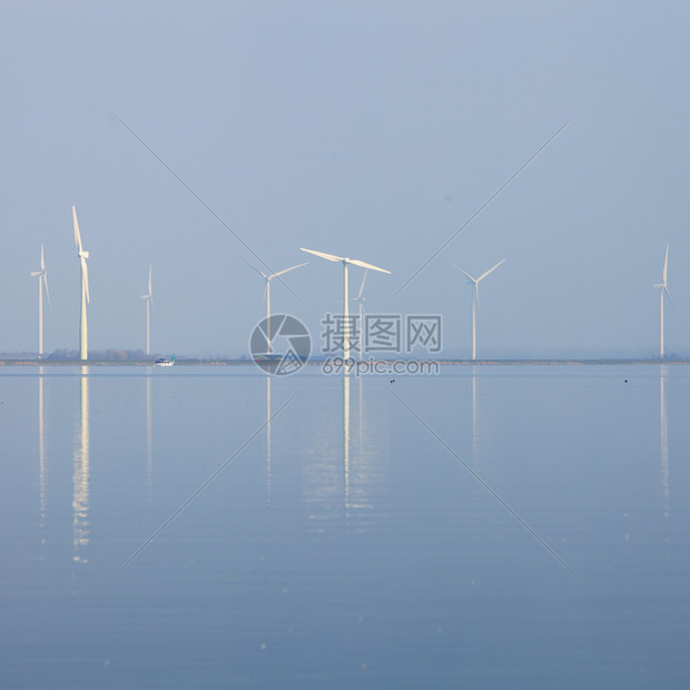 反映于内地Huizen附近Emr水中的风涡轮机和蓝天空图片
