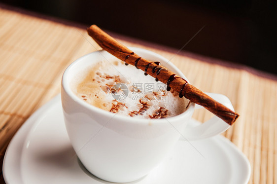 白杯咖啡加肉桂棒和木桌上巧克力酱图片