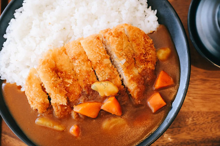 东京食种咖喱米饭用木制桌上的日本食煎猪肉背景