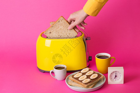 亮的有趣早餐粉红背景的黄面包机图片
