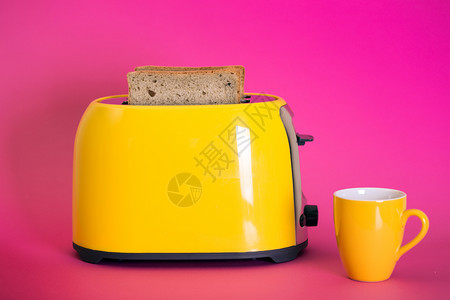 黄面包机和一杯粉红背景的咖啡图片