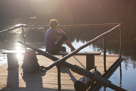 山湖女游客在日落时坐码头上图片