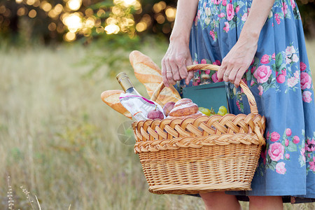 女孩拿着篮子野餐配有面包葡萄酒眼镜和卷饼图片