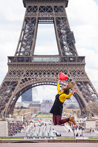 带着气球的快乐和微笑女学生以心形的气球跳过法国埃菲尔塔的背景图片