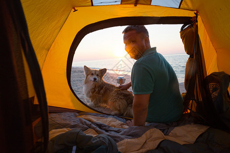 与一条狗在海滩的帐篷里男人黎明时分在海滩上图片