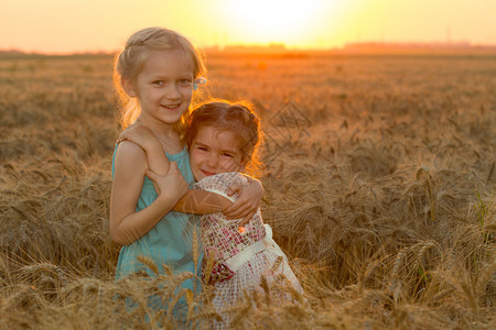 有两个女孩抱在看小麦田看日落图片