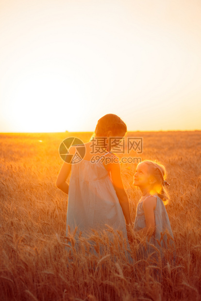 日落时年轻女孩在小麦田上欢乐图片