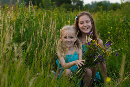 两姐妹坐在草丛中微笑着图片