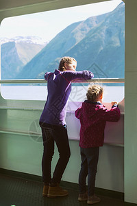 两个女孩站在渡轮上看着窗外山在背景北图片