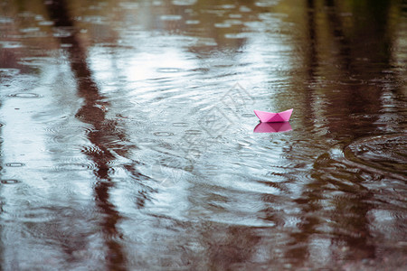雨中水坑的粉红色纸船图片