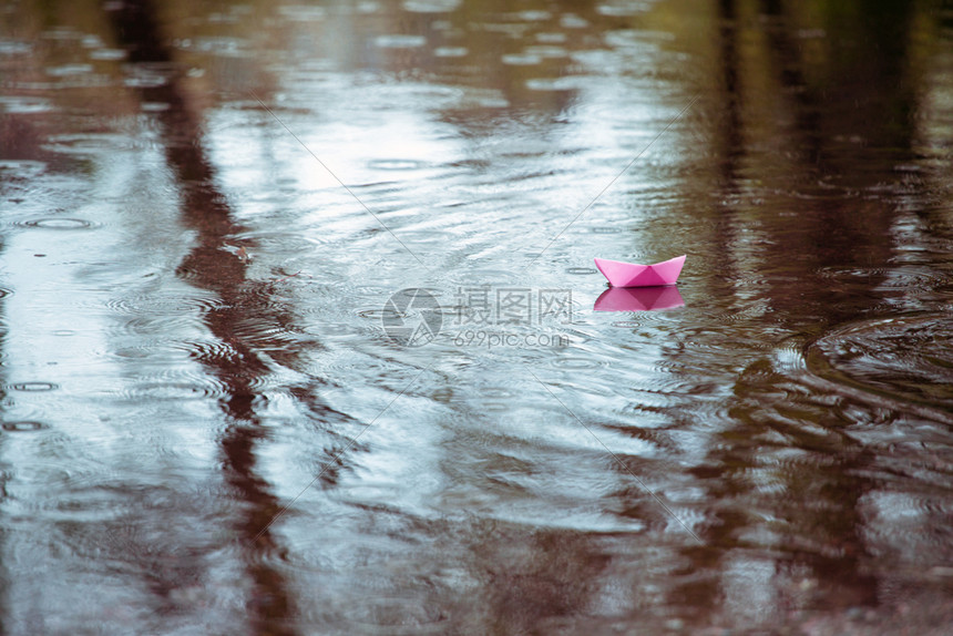 雨中水坑的粉红色纸船图片