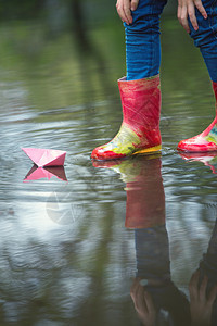 红色的雨鞋踩着水坑里玩着纸船图片