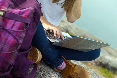女孩徒步旅行者笔记本电脑坐在岩石上特写图片