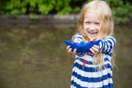 雨天过后带着蓝纸船的女孩在水坑里玩耍图片