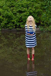 雨天过后带着蓝纸船的女孩在水坑里玩耍图片