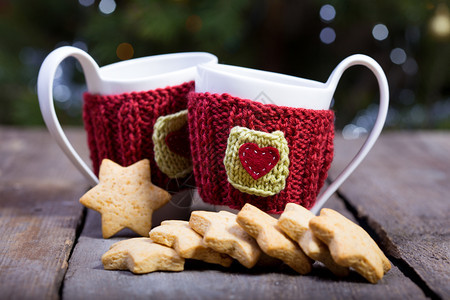 圣诞节编织的羊毛杯和在木制桌上的星形姜饼图片