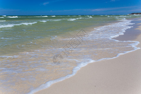 沙空海滨在清蓝天空有冲浪波图片