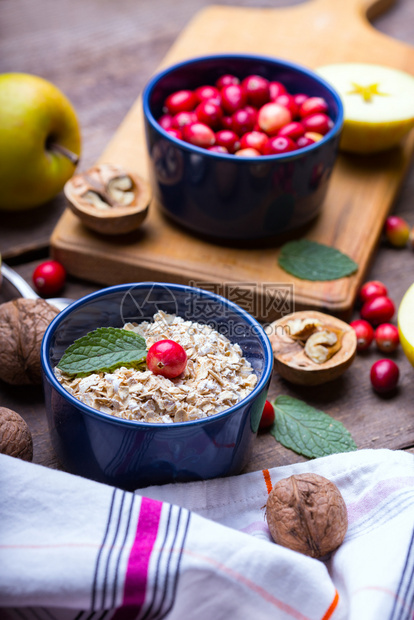 健康早餐燕麦红莓坚果木制桌上的苹果图片