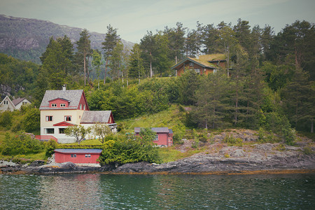 传统的挪威木制房屋站在湖边和山的偏远北图片
